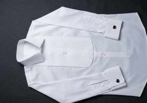 White tuxedo shirt flat lay showing pleated front, wingtip collar, and French cuffs with silver cufflinks